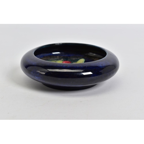 575 - A MOORCROFT POTTERY CIRCULAR TRINKET BOWL, dark blue ground with orchid design, impressed marks, app... 