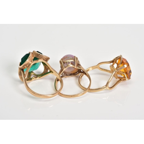 67 - THREE GEM SET RINGS, to include a cushion cut orange paste, within a four claw setting, to the bifur... 