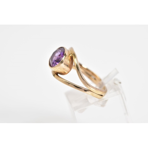 79 - AN AMETHYST SET RING, yellow metal ring set with an oval cut amethyst within a collect mount to the ... 