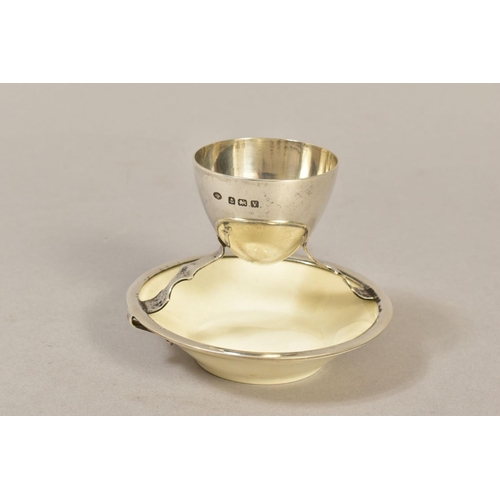 121 - A GEORGE V SILVER AND CERAMIC EGG CUP ATTRIBUTED TO A DESIGN BY CHRISTOPHER DRESSER, silver makers H... 
