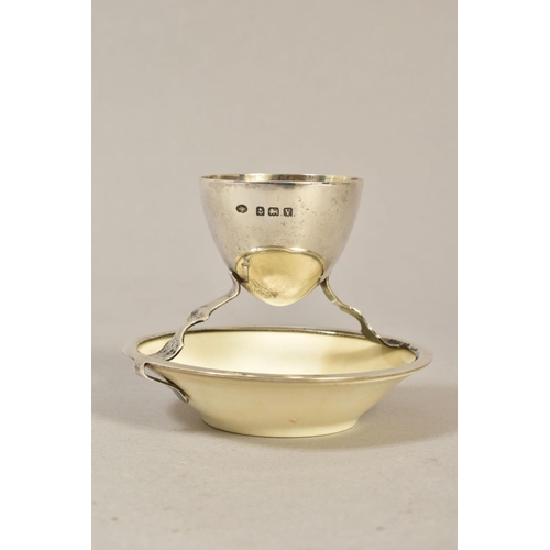 121 - A GEORGE V SILVER AND CERAMIC EGG CUP ATTRIBUTED TO A DESIGN BY CHRISTOPHER DRESSER, silver makers H... 
