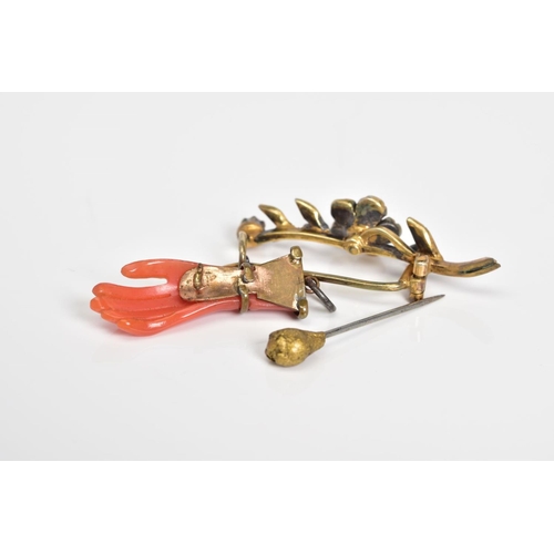 36 - THREE ITEMS OF JEWELLERY to include a carved hand pendant, a flower brooch set with circular coral c... 