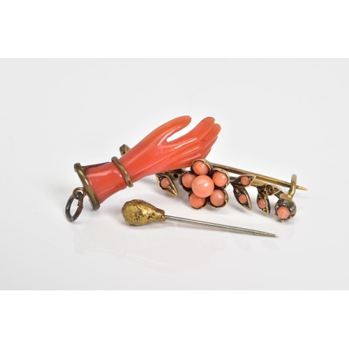 36 - THREE ITEMS OF JEWELLERY to include a carved hand pendant, a flower brooch set with circular coral c... 