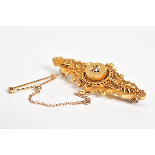 37 - AN EARLY 20TH CENTURY 15CT GOLD BROOCH, the embossed floral panel with a raised circular centre feat... 