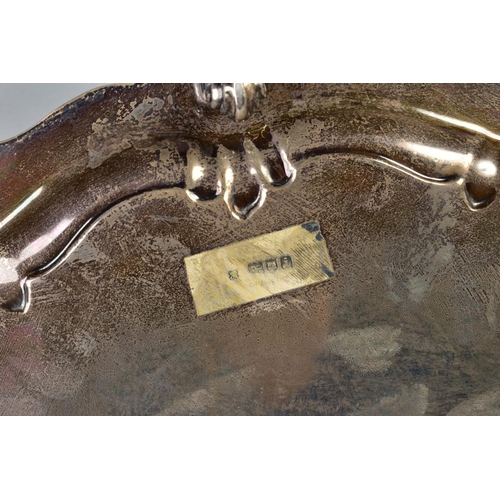 101 - AN EDWARDIAN SILVER CIRCULAR SALVER, cast foliate scroll rim, on three cabriole legs with scroll fee... 