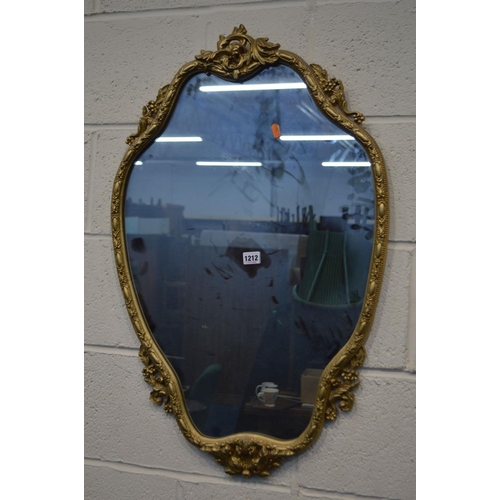 1212 - A LATE 20TH CENTURY FOLIATE GILT METAL SHAPED WALL MIRROR, 54cm x 86cm together with a similar gilt ... 