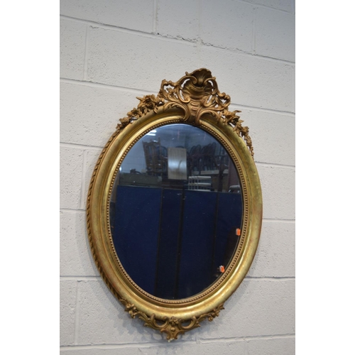 1250 - A 19TH CENTURY GILT FRAMED OVAL WALL MIRROR with gesso detailing to top and bottom edges and foliate... 