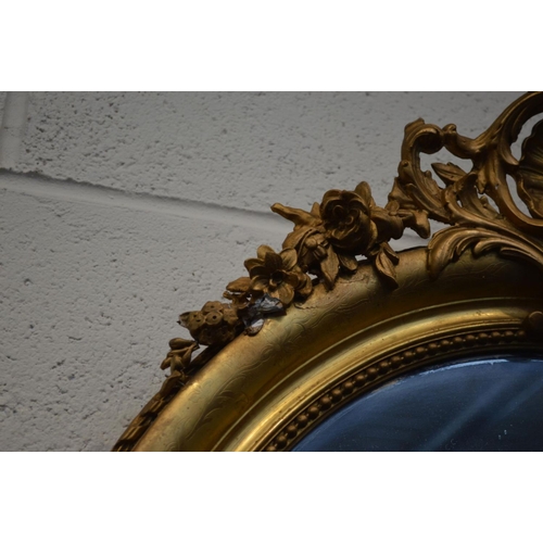 1250 - A 19TH CENTURY GILT FRAMED OVAL WALL MIRROR with gesso detailing to top and bottom edges and foliate... 