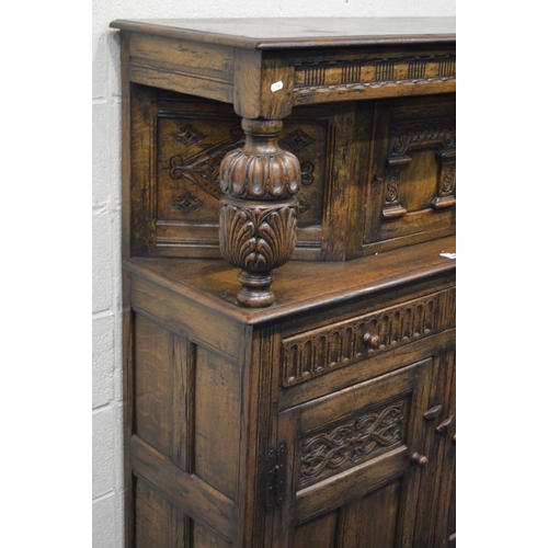 1296 - A REPRODUCTION OAK COURT CUPBOARD, the top section with a single cupboard door, between two acorn up... 