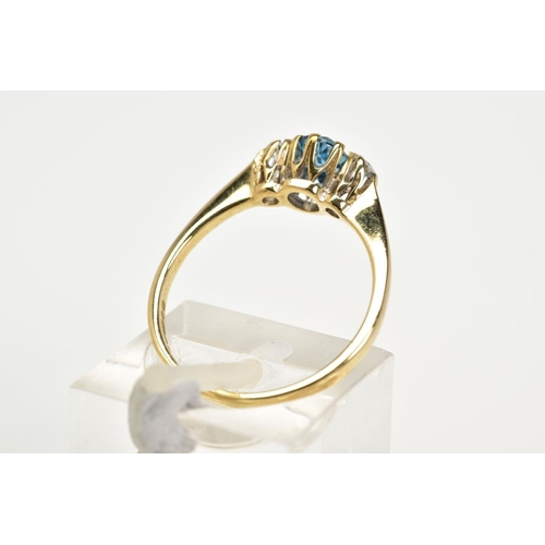 130 - A 9CT GOLD THREE STONE RING, designed with a claw set oval blue stone assessed as topaz, flanked by ... 