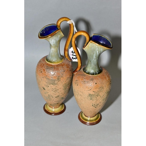 573 - A PAIR OF ROYAL DOULTON STONEWARE EWERS, blue and brown glazed handle and spout, impressed lace desi... 