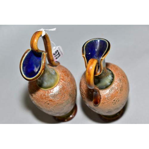 573 - A PAIR OF ROYAL DOULTON STONEWARE EWERS, blue and brown glazed handle and spout, impressed lace desi... 