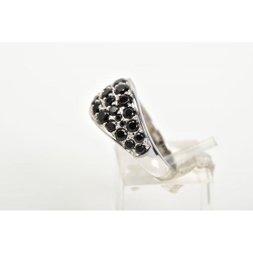 43 - A GEM SET RING, the white metal ring designed with an oval panel set with circular cut black stones ... 