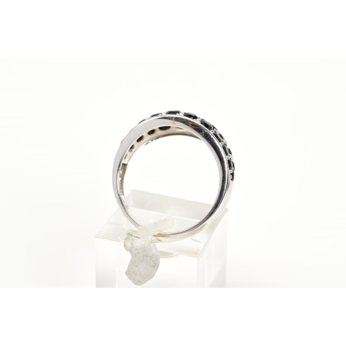 43 - A GEM SET RING, the white metal ring designed with an oval panel set with circular cut black stones ... 