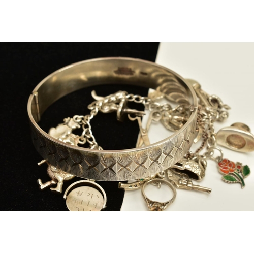 100 - A SILVER BANGLE AND CHARM BRACELET, the silver hinged bangle, with engraved detailing all round and ... 