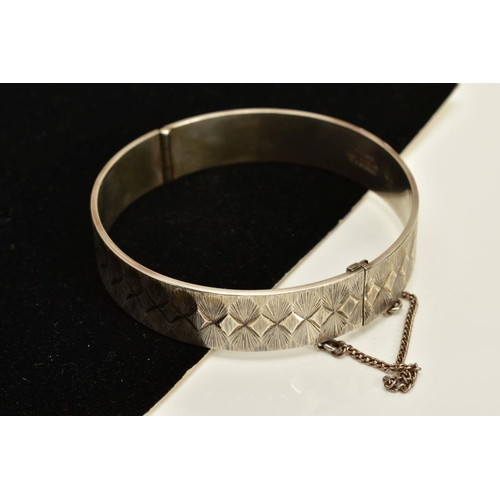 100 - A SILVER BANGLE AND CHARM BRACELET, the silver hinged bangle, with engraved detailing all round and ... 