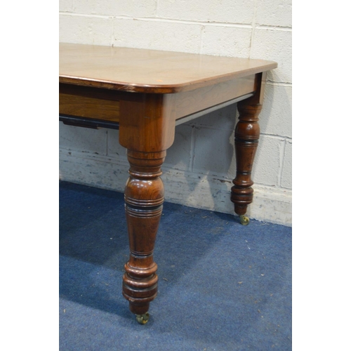 1245 - AN EDWARDIAN WALNUT DINING TABLE on turned legs and brass casters (adapted from a pull out table) wi... 