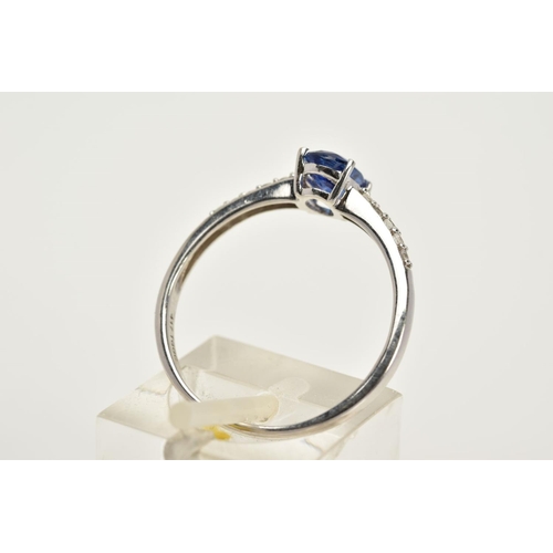 16 - A 9CT WHITE GOLD RING, designed with a claw set oval blue stone, assessed as Kyanite, circular cut c... 