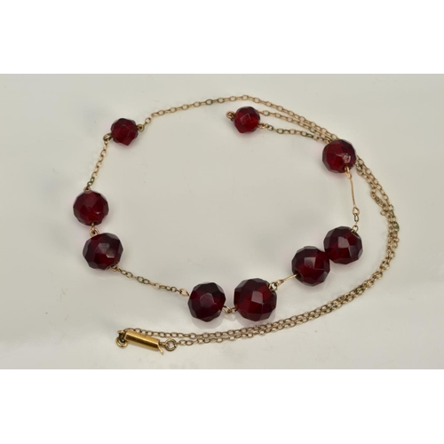 18 - A YELLOW METAL BEADED NECKLACE, designed with a row of nine graduated faceted red beads, assessed as... 