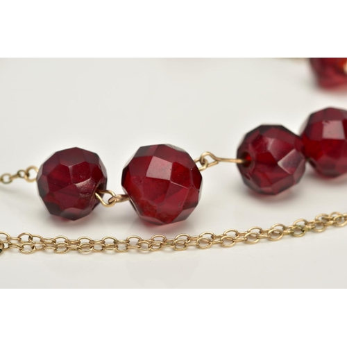 18 - A YELLOW METAL BEADED NECKLACE, designed with a row of nine graduated faceted red beads, assessed as... 