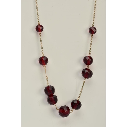 18 - A YELLOW METAL BEADED NECKLACE, designed with a row of nine graduated faceted red beads, assessed as... 