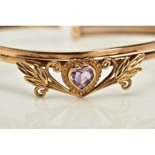 21 - A YELLOW METAL AMETHYST BANGLE, designed with a floral panel set with a heart cut amethyst, fitted t... 