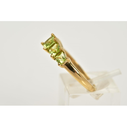 41 - A 9CT GOLD PERIDOT RING, designed with a tiered row of claw set, square cut peridots, to a plain pol... 