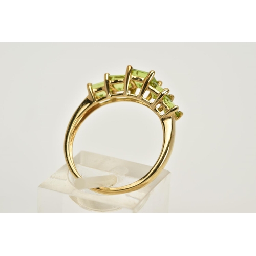 41 - A 9CT GOLD PERIDOT RING, designed with a tiered row of claw set, square cut peridots, to a plain pol... 