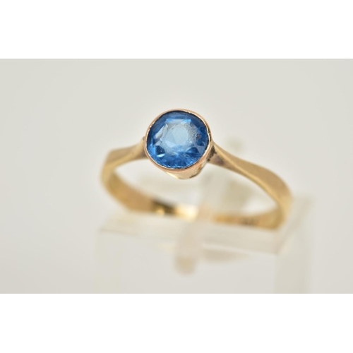 51 - A YELLOW METAL GEM SET RING, set with a circular cut blue stone assessed as paste, tapered shoulders... 