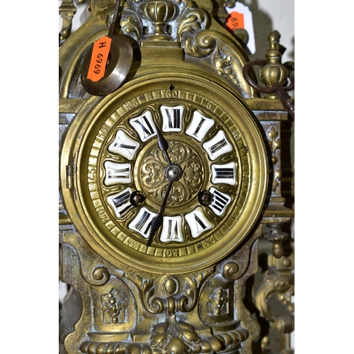 612 - A LATE 19TH CENTURY BRASS MANTEL CLOCK OF ORNATE DESIGN, enamelled Roman numerals, eight day movemen... 