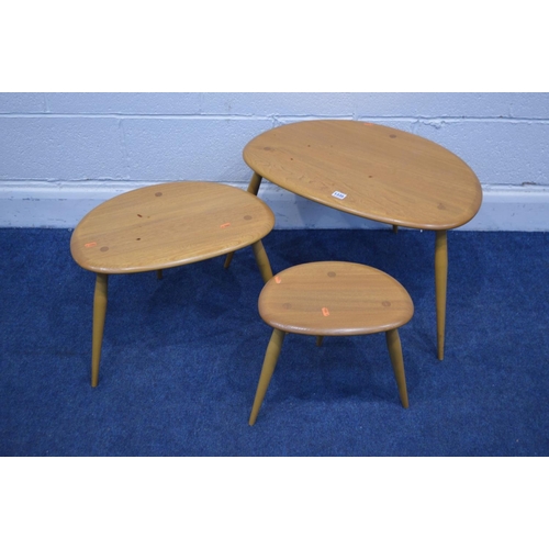 1335 - AN ERCOL BLONDE ELM NEST OF THREE PEBBLE TABLES, model 354, on cylindrical out splayed legs, largest... 