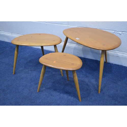 1335 - AN ERCOL BLONDE ELM NEST OF THREE PEBBLE TABLES, model 354, on cylindrical out splayed legs, largest... 