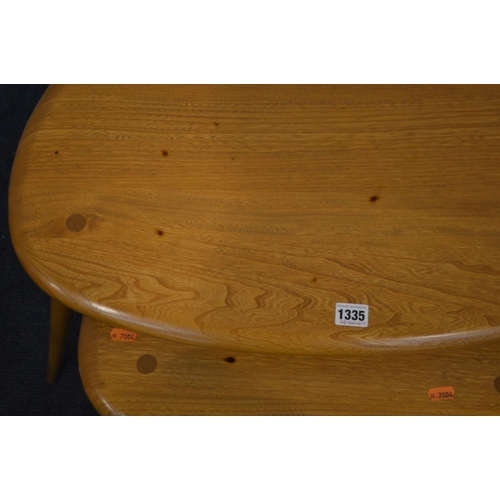 1335 - AN ERCOL BLONDE ELM NEST OF THREE PEBBLE TABLES, model 354, on cylindrical out splayed legs, largest... 