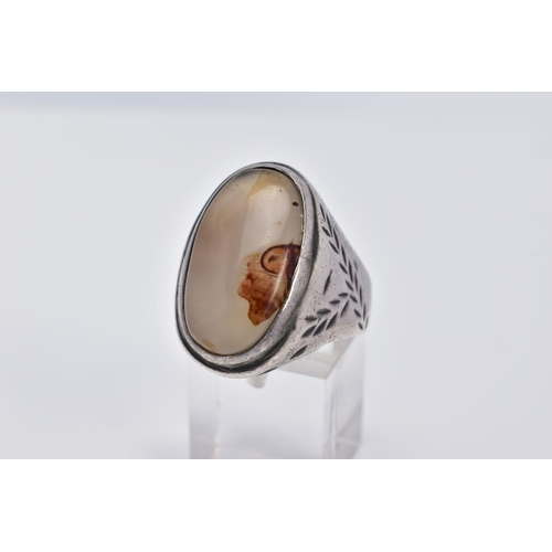 32 - A WHITE METAL GEM SET RING, of oval design set with a cabochon cloudy stone assessed as agate, withi... 