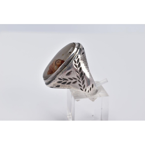 32 - A WHITE METAL GEM SET RING, of oval design set with a cabochon cloudy stone assessed as agate, withi... 