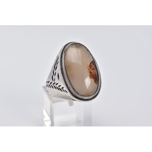 32 - A WHITE METAL GEM SET RING, of oval design set with a cabochon cloudy stone assessed as agate, withi... 