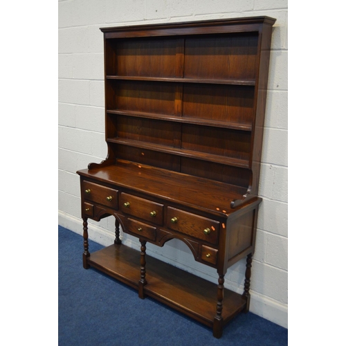 1252 - A REPRODUCTION OAK DRESSER, with a three tier plate rack above a base with six various drawers, on t... 