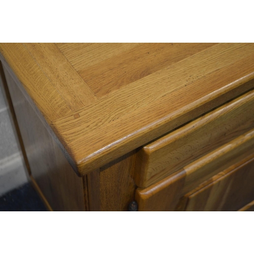 1335 - A SOLID GOLDEN OAK SIDEBOARD, with two drawers above double fielded panel cupboard doors, width 141c... 