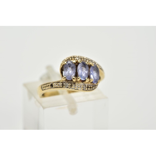 59 - A THREE STONE CROSS OVER RING, designed with three oval cut iolite, within single cut diamond detail... 