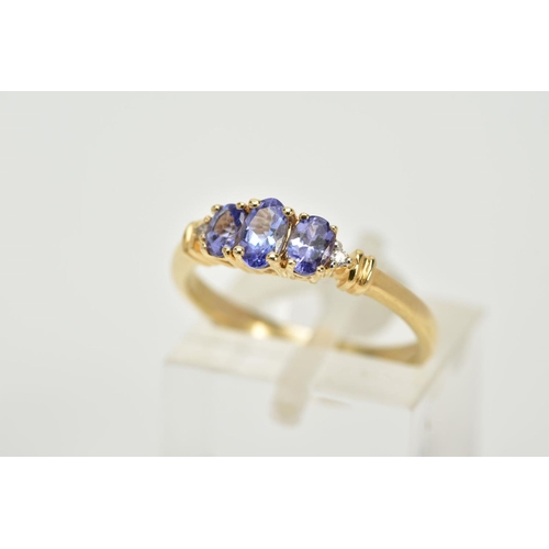 61 - A 14CT GOLD THREE STONE TANZANITE RING, designed with three graduated, oval cut tanzanite stones, fl... 