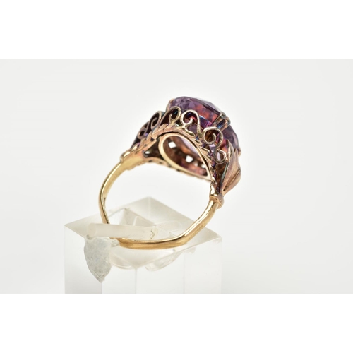 72 - A 9CT GOLD AMETHYST RING, designed with a double claw set, oval cut amethyst, within an openwork scr... 