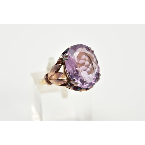 72 - A 9CT GOLD AMETHYST RING, designed with a double claw set, oval cut amethyst, within an openwork scr... 