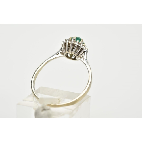 77 - A WHITE METAL EMERALD AND DIAMOND CLUSTER RING, designed with a central circular cut emerald within ... 