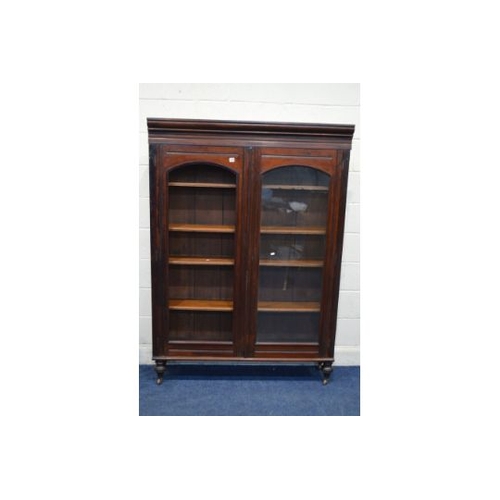 1344 - AN EDWARDIAN MAHOGANY DOUBLE DOOR BOOKCASE on turned legs with ceramic casters, width 130cm x depth ... 