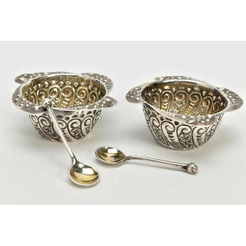 142 - A PAIR OF SILVER SALTS AND SPOONS, each salt with a scroll engraved body, wavy scroll detailed rim, ... 