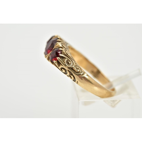 38 - A 9CT GOLD THREE STONE GARNET RING, set with three graduated circular cut garnets, within a scroll d... 