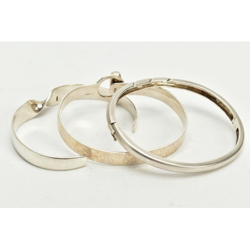 50 - THREE SILVER BANGLES, the first a twist cuff hallmarked London, together with a silver hinged bangle... 