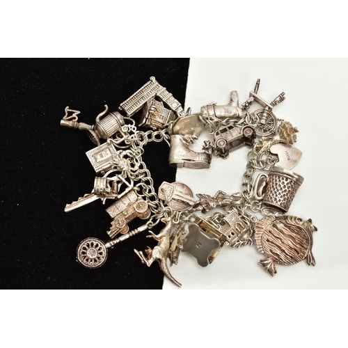 57 - A WHITE METAL CHARM BRACELET, suspending twenty-seven charms in forms such as a house, web,boots, wi... 