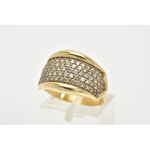 66 - A YELLOW METAL DRESS RING, designed as a slightly curved panel set with colourless stones assessed a... 