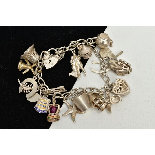 47 - A WHITE METAL CHARM BRACELET, suspending nineteen charms in forms such as a heart shaped jewellery b... 